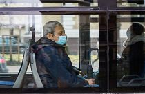 A man wearing a protective face mask sits in a city bus in Latvia.