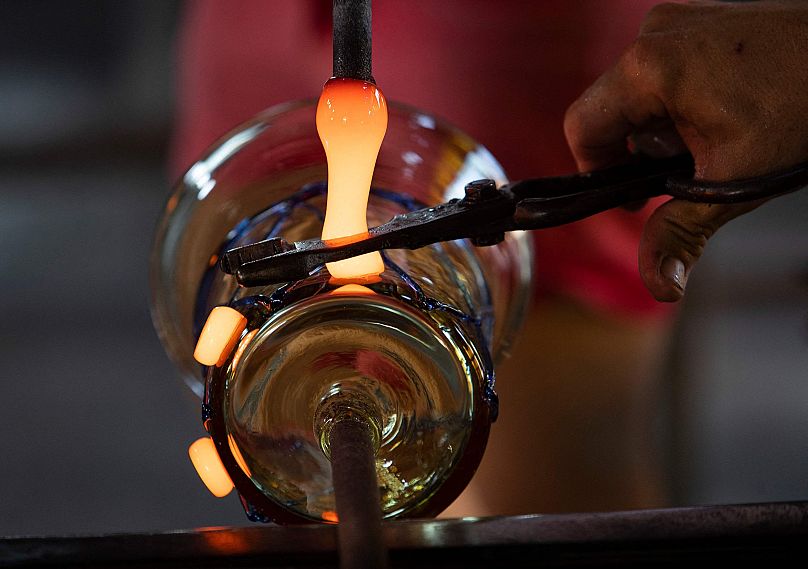 A master craftsman cuts glowing glass as he works a piece at the Vidrios Guardiola glass factory in Algaida, on the island of Mallorca, Spain, Aug. 27, 2021.