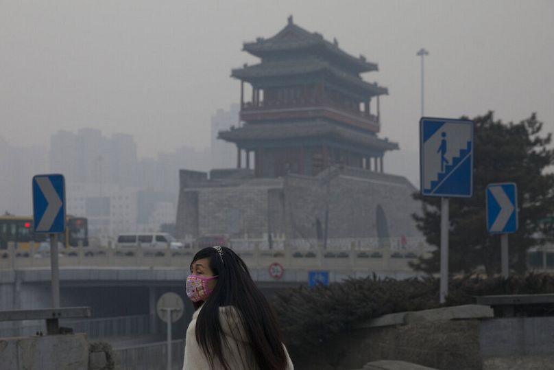 A woman wears a mask as she walks under smog in Beijing, February 2014