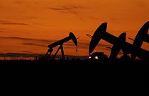 Un camión pasa entre extractores de petróleo al atardecer cerca de Karnes City, Texas, el miércoles 1 de noviembre de 2023.