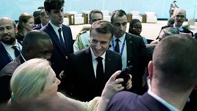 France President Emmanuel Macron takes photos with people as he attends COP28.