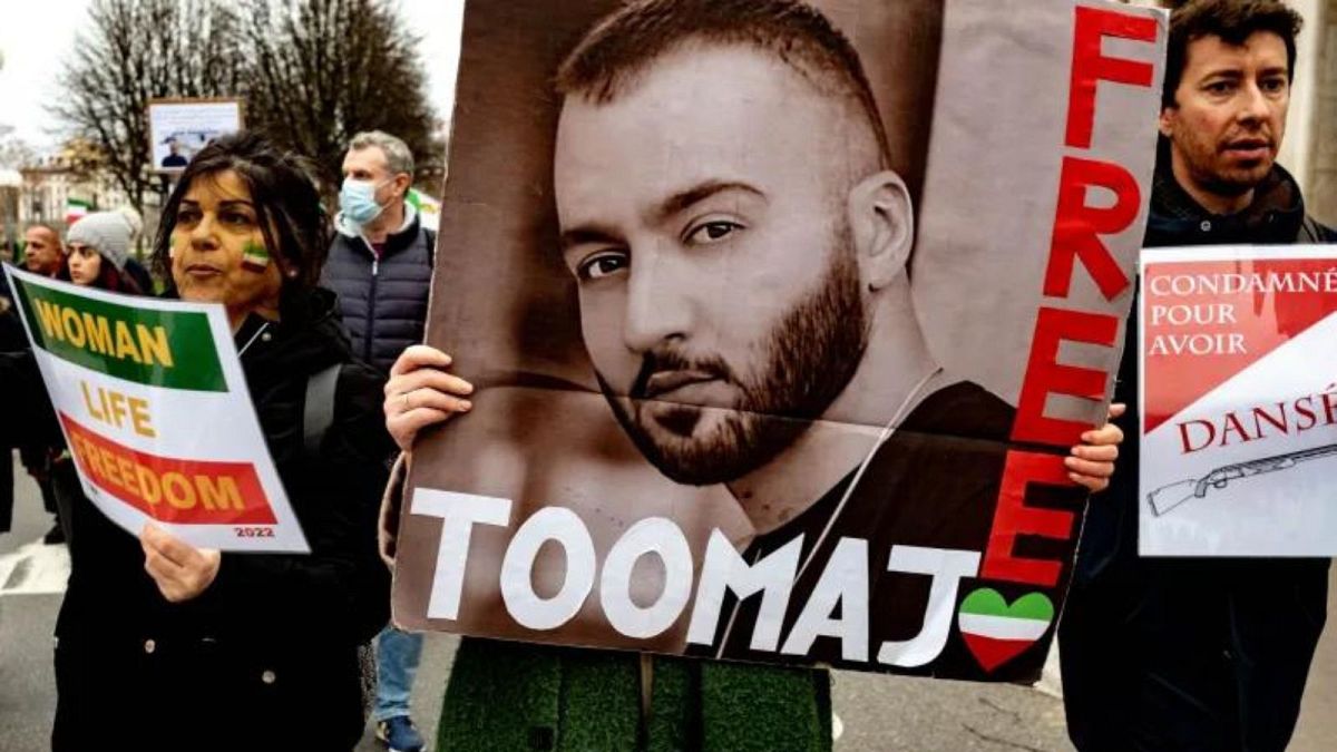 A woman holds a poster of rapper Toomaj Salehi, who was arrested over his support of the Mahsa Amini protests