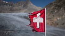 A photograph taken on August 24, 2023 above Gletsch, in the Alps shows a frayed Swiss flag next to insulating foam covering a part of the Rhone Glacier to prevent it from melt