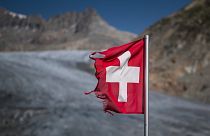 A photograph taken on August 24, 2023 above Gletsch, in the Alps shows a frayed Swiss flag next to insulating foam covering a part of the Rhone Glacier to prevent it from melt