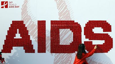 A woman attaches a condom on the board during an AIDS awareness campaign in South Korea, 2011.