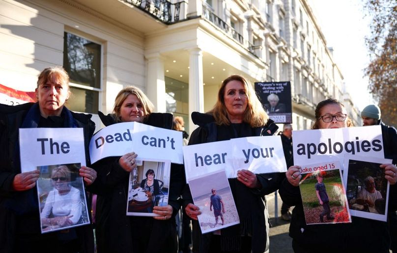 Protesters holds a placard reading "The dead can't hear your apologies" during a gathering outside the UK Covid-19 Inquiry building in west London