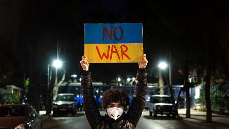 ARCHIVO - Un manifestante sostiene una pancarta durante una protesta contra la invasión rusa de Ucrania, frente a la embajada rusa en Atenas, el viernes 25 de febrero de 2022.
