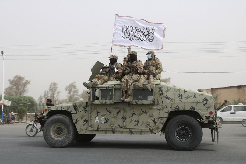 Taliban fighters patrol on the road during a celebration marking the second anniversary of the withdrawal of US-led troops in Kandahar, August 2023