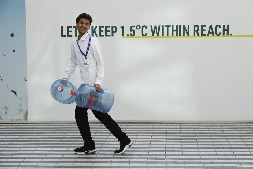A man carries water containers ahead of the COP28 UN Climate Summit, November 2023