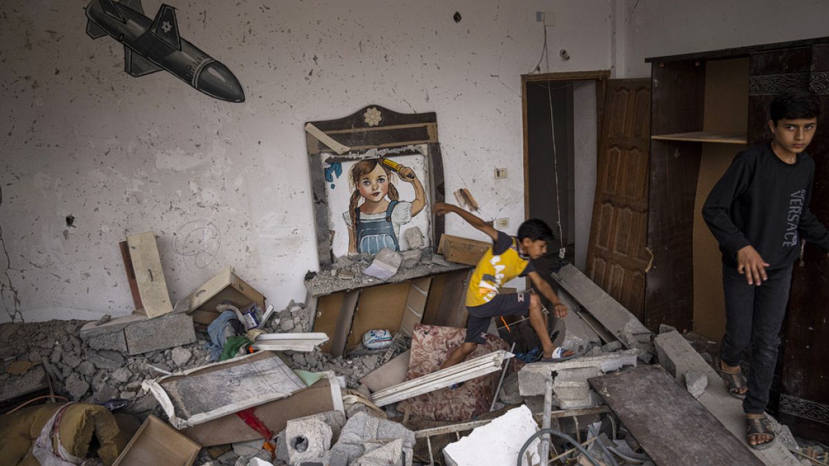 Gazze Şeridi'nden duvarında roket boyaması olan İsrail tarafından vurulan bir evde oynayan çocuklar.