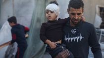 Палестинец несёт ребёнка, пострадавшего во время израильской бомбардировки, Рафах, 2 декабря 2023 года.