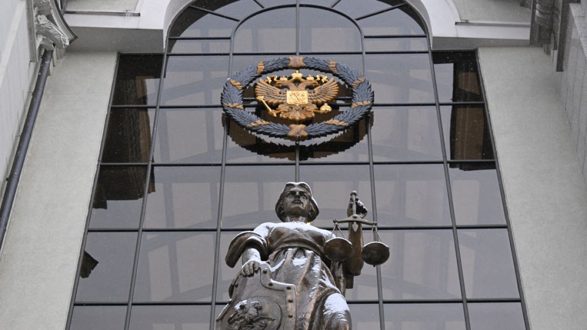 Статуя Фемиды, древнегреческой богини правосудия, и государственный герб России у входа в Верховный суд РФ в Москве