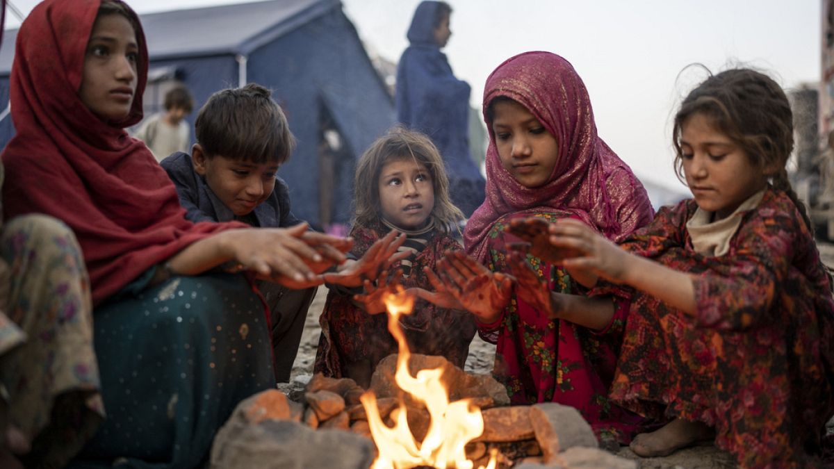 کودکان پناهنده افغان در اردوگاهی در تورخم در مز پاکستان و افغانستان دور آتشی خود را گرم می‌کنند، عکس نوامبر ۲۰۲۳ میلادی