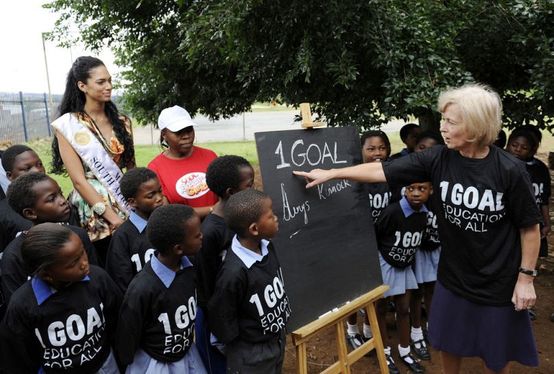 Baroness Glenys Kinnock (R) and Miss South Africa 2008 Tatum Keshwar (L) pose with pupils of a school in Soweto for the 1GOAL campaign in 2009