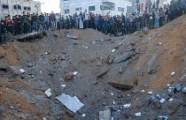 يتجمع السكان في رفح حول حفرة سببها صاروخ إسرائيلي على أحد المباني السكنية