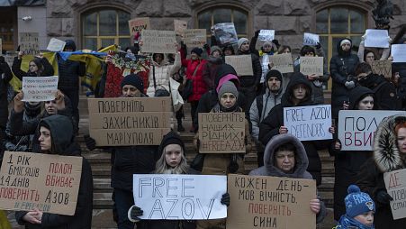 People hold posters reading "Return defenders of Mariupol", "Free Azov", and others, during a demonstration in central Kyiv, Ukraine, Sunday, Dec. 3, 2023. The demonstration o