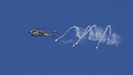 An Israeli military helicopter releases flares over the Israel-Gaza border as seen from southern Israel, Monday, Dec. 4, 2023. 