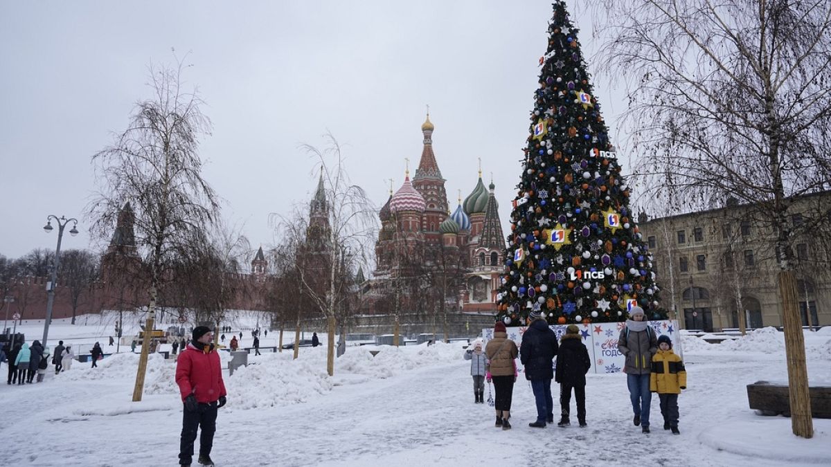 Люди проходят мимо рождественской елки в парке Зарядье рядом с Кремлем и Красной площадью после снегопада в Москве, Россия, вторник, 28 ноября 2023 года.