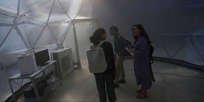 مجموعة من الزوار داخل إحدى القبب الهندسية التي صُمِّمَت لمحاكاة جودة الهواء في ثلاث مدن عالمية