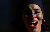 A woman, her face painted with the colours of the national flag, sings during the closing campaign on the Venezuela Referendum on dispute territory with Guyana.