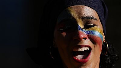 A woman, her face painted with the colours of the national flag, sings during the closing campaign on the Venezuela Referendum on dispute territory with Guyana.