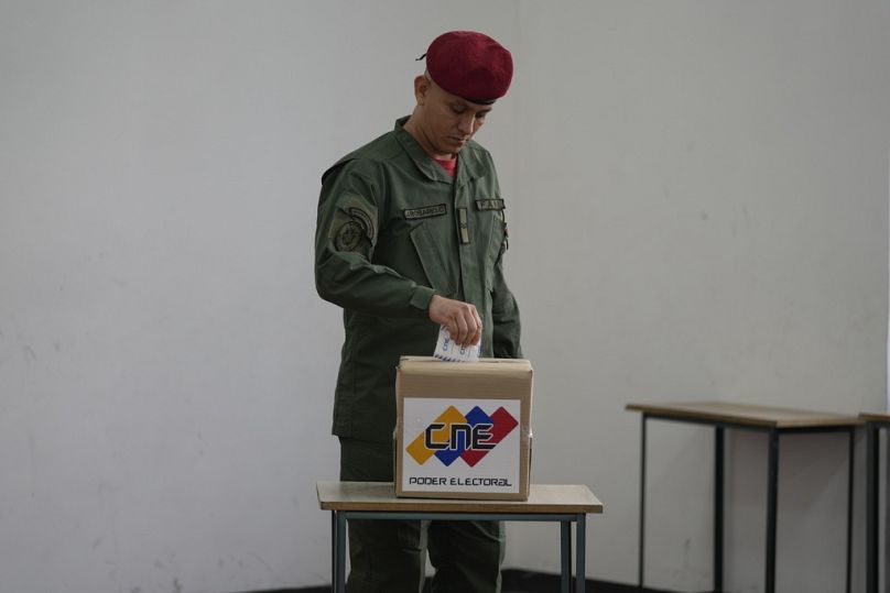 A soldier places his electronic voting receipt into a ballot box during a referendum about the future of a disputed territory with Guyana, at a polling station in Caracas.