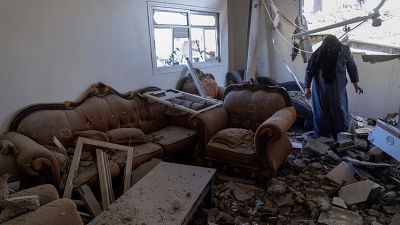 سيدة تتفقد أثر الدمار الذي خلقته غارة إسرائيلية على بيتها في خان يونس