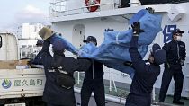 Miembros de la Guardia Costera Japonesa cargan restos de la aeronave militar estadounidense Osprey en un puerto este lunes en la prefectura de Kagoshima