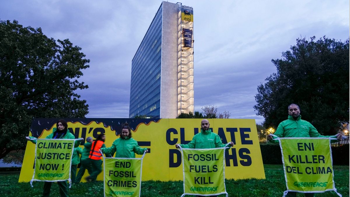 نشطاء منظمة السلام الأخضر البيئية يرفعون لافتات على الجانب وبجوار مبنى المقر الرئيسي لشركة ENI، شركة النفط والغاز الإيطالية، في روما، الثلاثاء، 5 ديسمبر 2023.