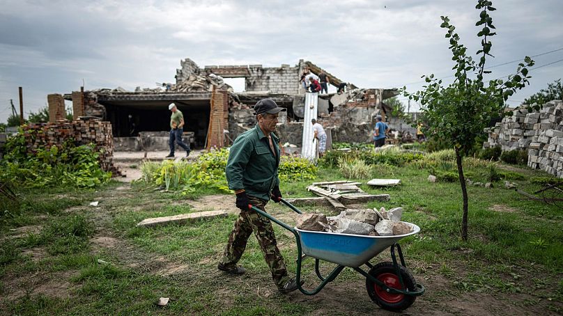 Волонтер тащит тележку с мусором во время расчистки дома Жанны и Сергея Динаевых, разрушенного в результате российских бомбардировок, недалеко от Чернигова.