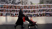 Eine Frau geht in Jerusalem mit ihrem Kinderwagen vor Bildern der Geiseln vorbei, 3. Dezember
