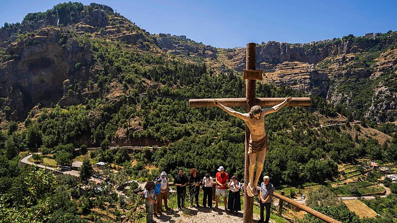 Lebanese priest Hani Tawk, centre, prays with French tourists and his family outside the Saint Elisha monastery in the Kadisha Valley, 22 July 2023.