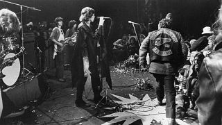 Mick Jagger sings at the Altamont Rock Festival at Livermore, Calif. on Saturday, December 6, 1969 while Hells Angels cross stage during melee to help fellow motorcyclists. 