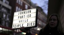 Баннер в руках протестующего "Джонсон тусовался, пока люди умирали"