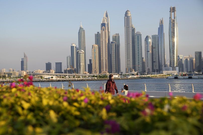 Des personnes marchent avec la ligne d'horizon en arrière-plan alors que Dubaï, aux Émirats arabes unis, accueille le sommet de l'ONU sur le climat COP28, le mardi 5 décembre