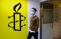 رجل يمر أمام شعار منظمة العفو الدولية في مكتبها في هونغ كونغ الاثنين 25 أكتوبر 2021