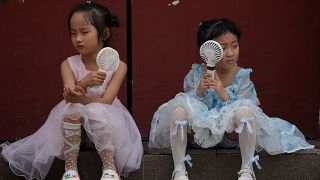 طفلتان تحملان مروحتين في يوم حار بالعاصمة الصينية بكين، أرشيف، صيف عام 2023