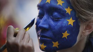 Una donna si fa dipingere il volto come la bandiera dell'UE durante un festival fuori dal Parlamento europeo a Bruxelles, domenica 26 maggio 2019\. 