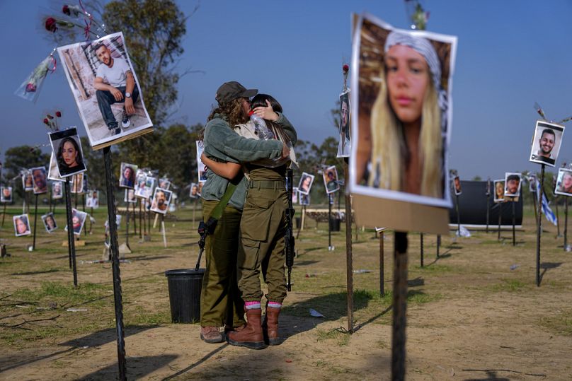 Des soldats israéliens s'enlacent près des photos des personnes tuées ou capturées par le Hamas au festival de musique Nova, au sud d'Israël. Photo prise en décembre 2023