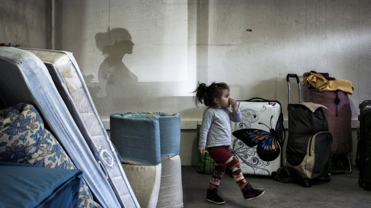 Une jeune fille marche au milieu de sacs et de matelas alors que des migrants d'Europe de l'Est attendent un accueil temporaire à Décines, dans le centre-est de la France.