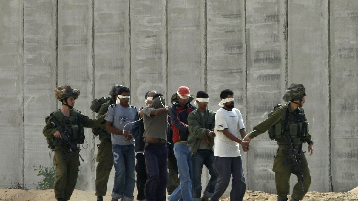 جنود إسرائيليون يرافقون أسرى فلسطينيين معصوبي الأعين بالقرب من غزة 