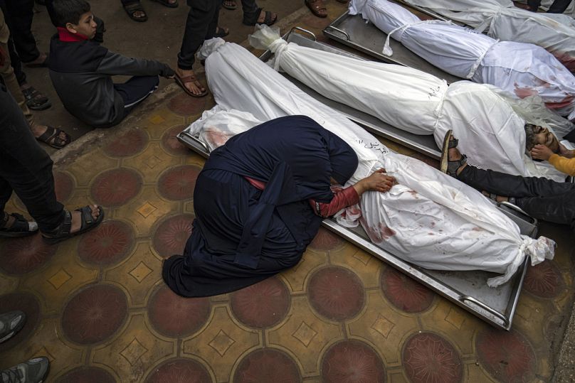 A woman mourns the covered bodies of her child and her husband killed in an Israeli army bombardment of the Gaza Strip, in the hospital in Khan Younis.