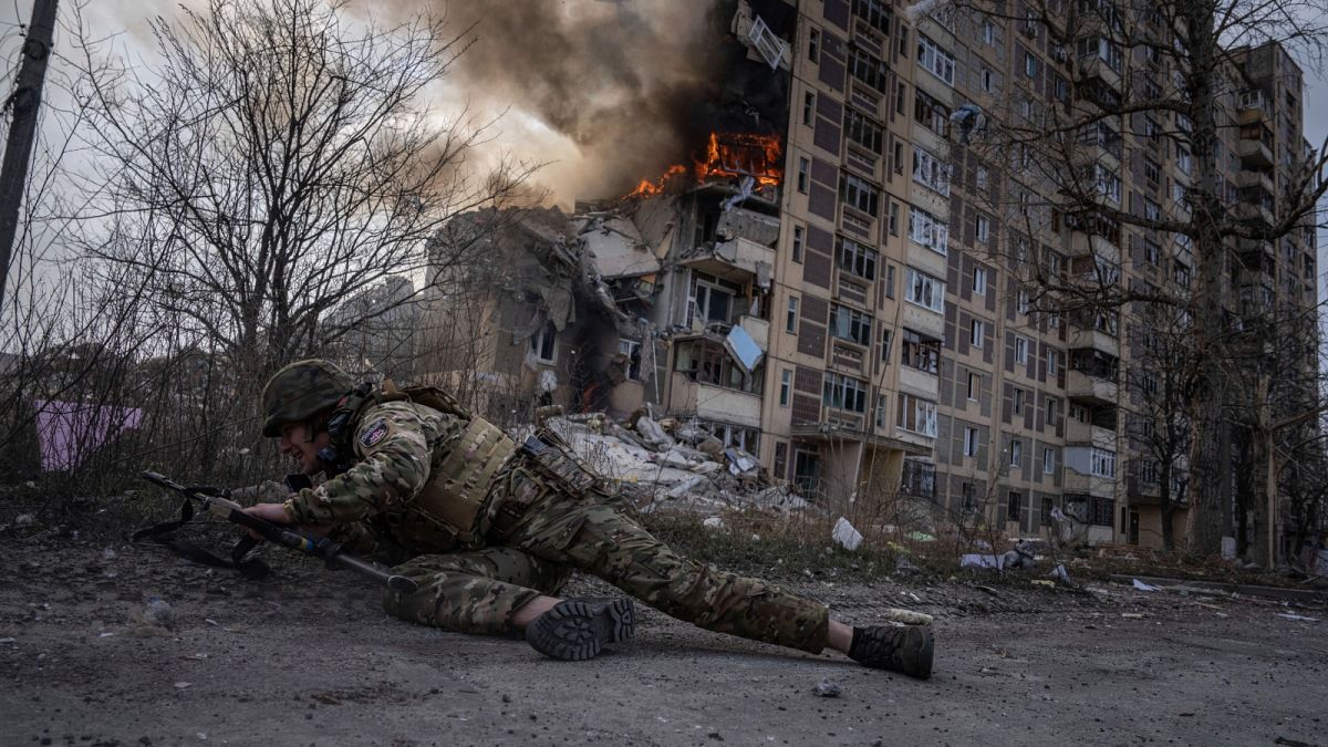 جندي أوكراني يحتمي أمام مبنى محترق استهدف خلال غارة جوية روسية في أفدييفكا-أوكرانيا