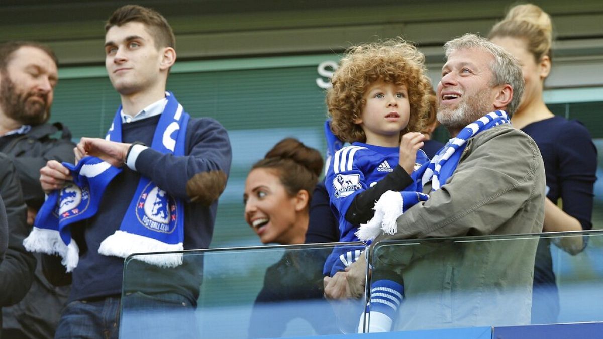 Chelsea owner Roman Abramovich smiles as he holds his son Aaron as his other son Arkadiy looks on at left after the English Premier League soccer match.
