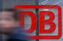 A commuter walks past the logo of German national railway operator Deutsche Bahn DB at the main station of Frankfurt am Main, western Germany.