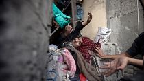 فلسطينيون يحاولون إنقاذ امرأة عالقة تحت أنقاض مبنى مدمر في أعقاب الغارات الجوية الإسرائيلية في مخيم خان يونس للاجئين