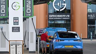 A driver connects their car to a charing point at Gridserve E-charging station for all-electric cars, near Braintree, eastern England on August 8, 2023. Justin TALLIS / AFP
