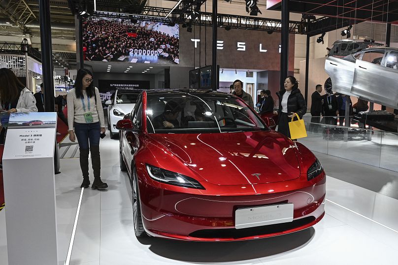 People try Tesla’s electric vehicle Model 3 at its booth during the China International Supply Chain Expo (CISCE) in Beijing on December 1, 2023. JADE GAO / AFP