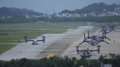 Американский транспортный самолет MV-22B Osprey (слева) выруливает после полета обратно на авиабазу Корпуса морской пехоты США Футенма в Гиноване, к югу от Окинавы, Япония