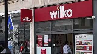 Un cycliste passe devant une succursale de "Wilko" dans l'ouest de Londres le 3 août 2023\. Wilko, le 3 août, a annoncé son intention de nommer des administrateurs, ce qui pourrait entraîner la suppression de 12 000 emplois.